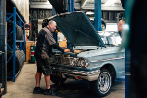 Technician working on a classic car on the hoist